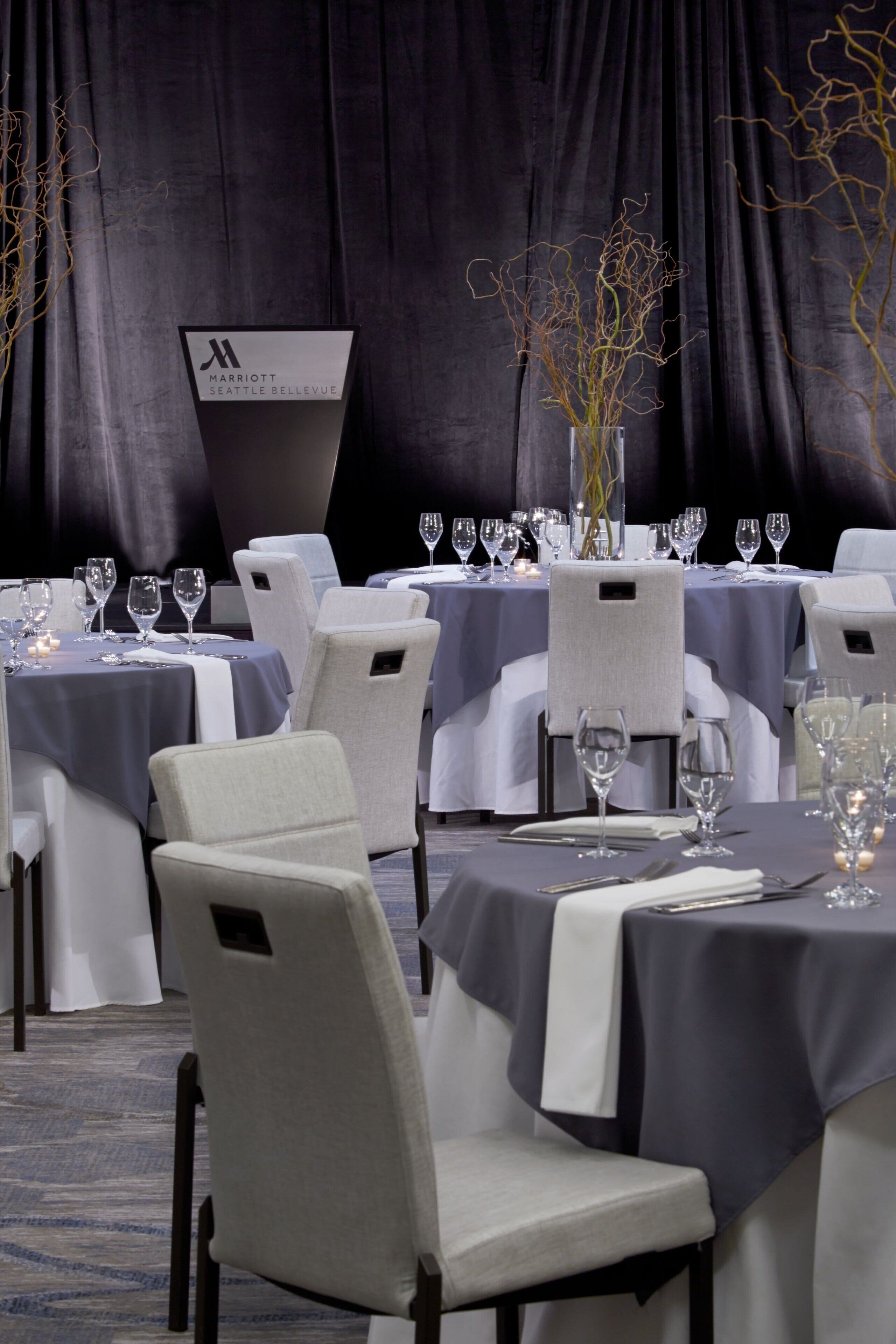 A hotel dining area with tables set for a meal, chairs, and a sign indicating the hotel name.
