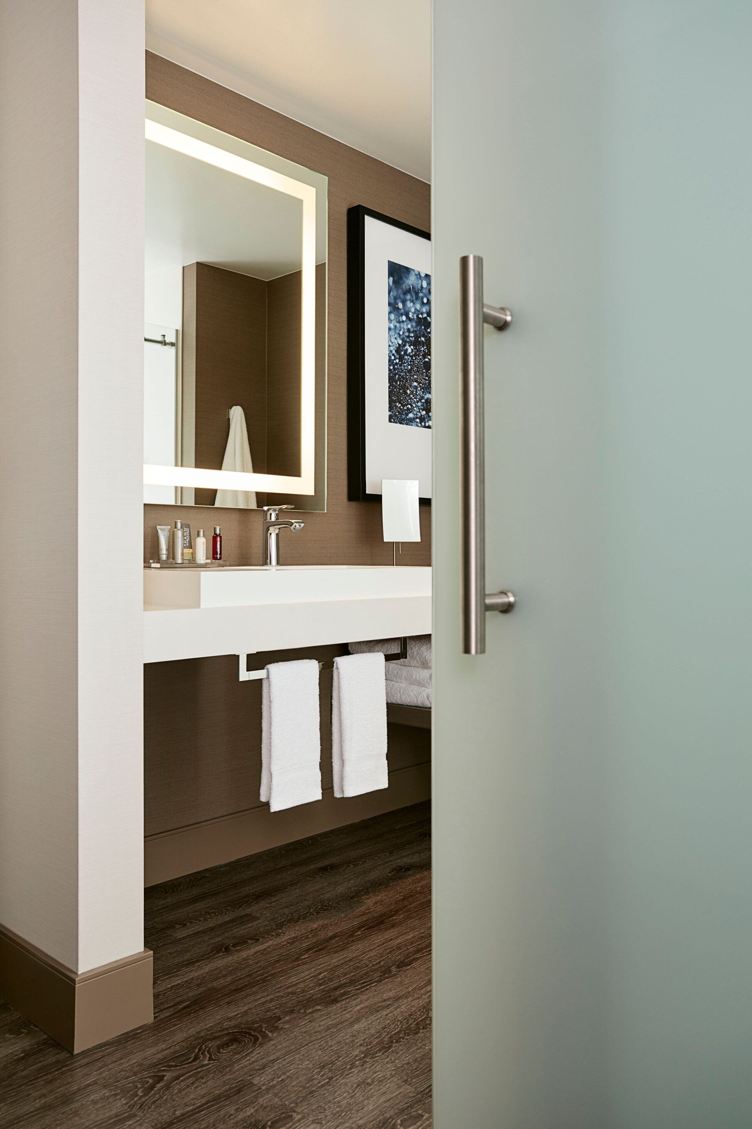 Un baño moderno con tocador blanco, un espejo grande y un perchero para toallas.