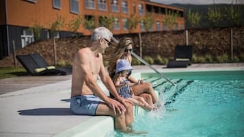 Guests can enjoy a refreshing swim in the pool surrounded by lounge chairs and a low wall.