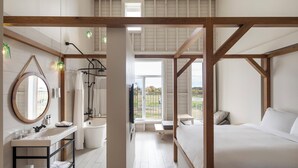 Un dormitorio moderno con estructura de techo de madera, una cama grande, una mesita de noche y vistas al exterior.