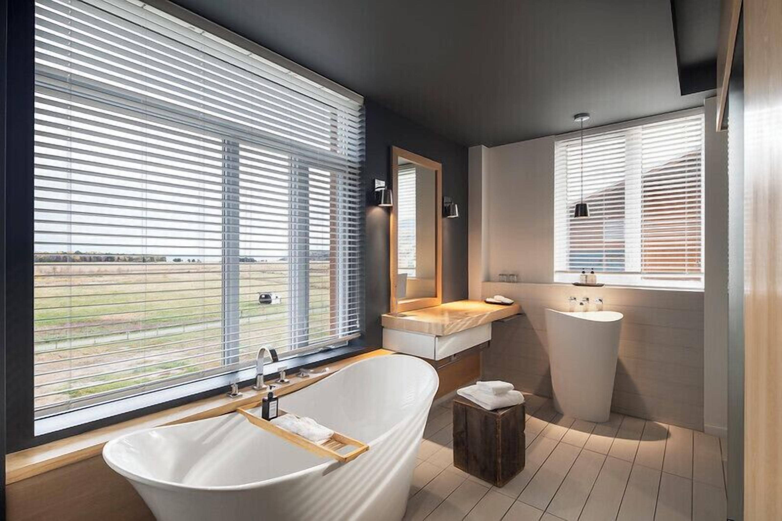 A modern bathroom with a freestanding bathtub, a vanity with a mirror, and a standalone sink.
