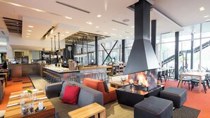 Un vestíbulo de hotel moderno con chimenea, zonas de estar y un bar.