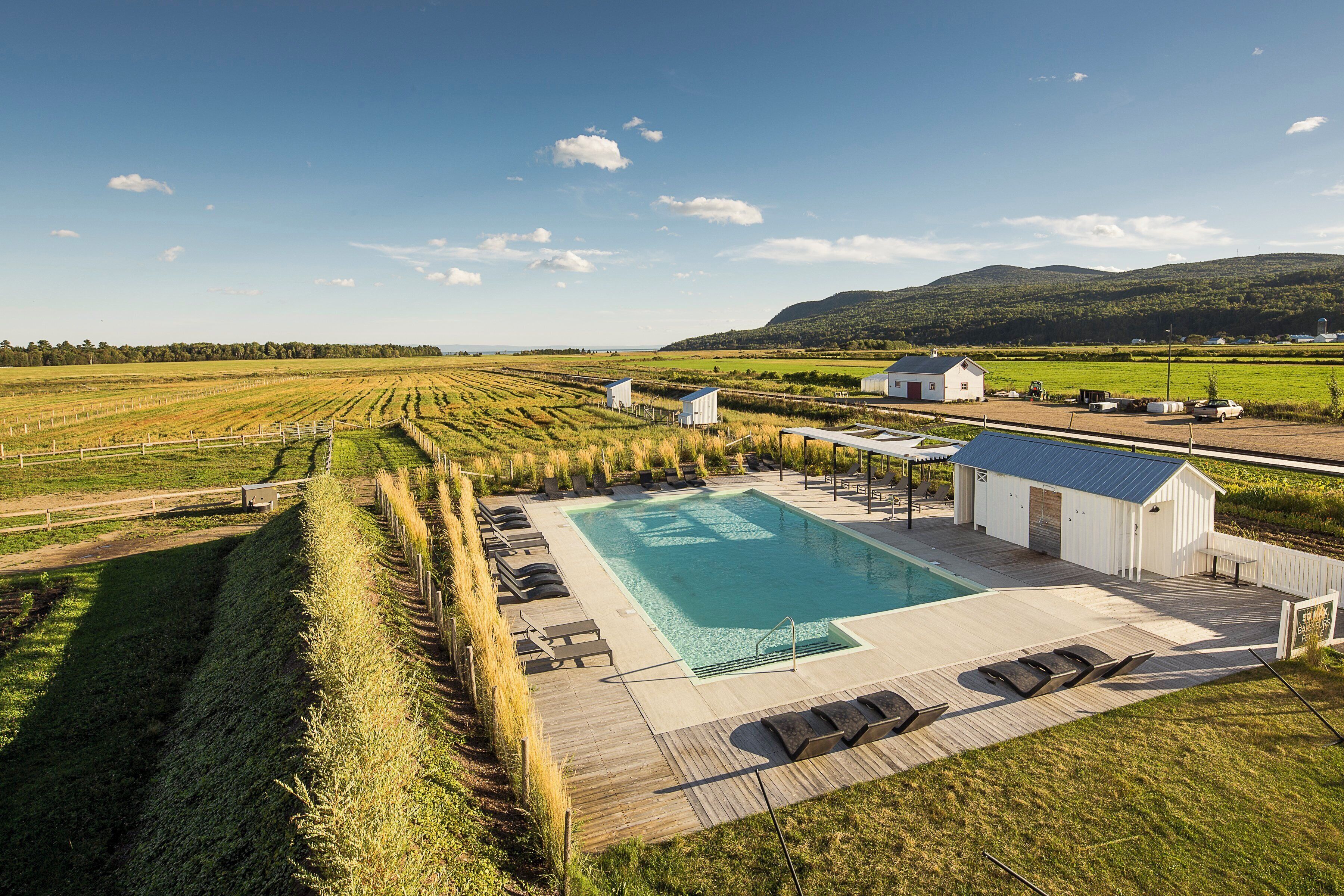 Ein Poolbereich mit Liegestühlen, einer kleinen Gartenhütte und Blick auf die umliegenden Felder und Hügel.