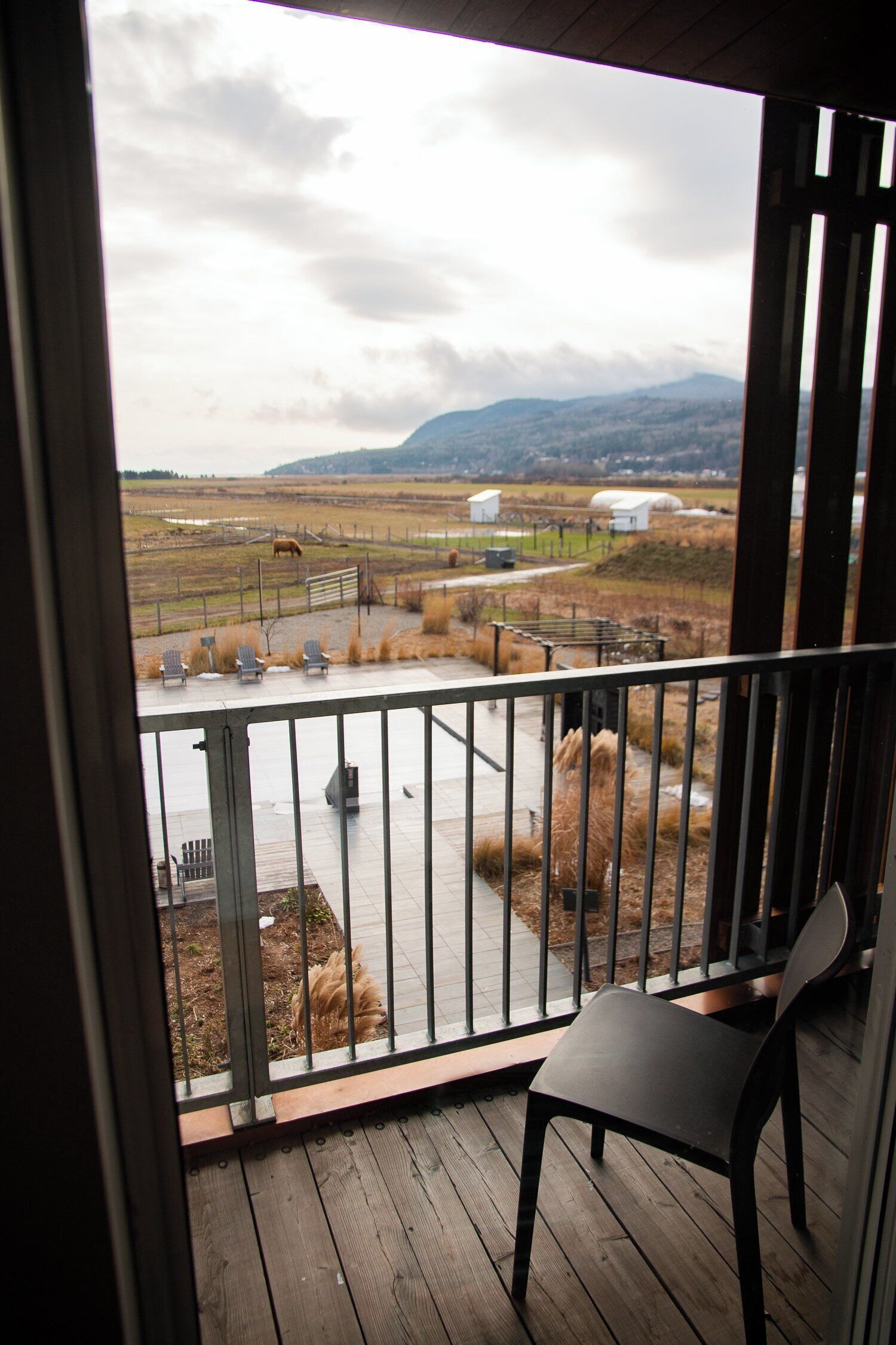 Un balcon offrant une vue sur un paysage rural, avec des champs et des montagnes à l’horizon.