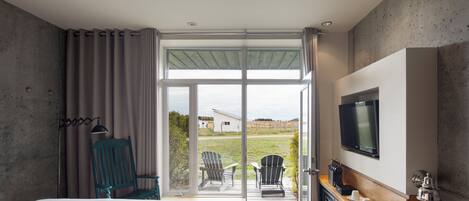 Ein modernes Hotelzimmer mit Bett, Fernseher, Schreibtisch mit Kaffeemaschine und Blick ins Freie.