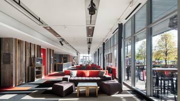 Un espacio interior amplio con un largo banco, asientos rojos y grandes ventanales que ofrecen vistas al exterior.