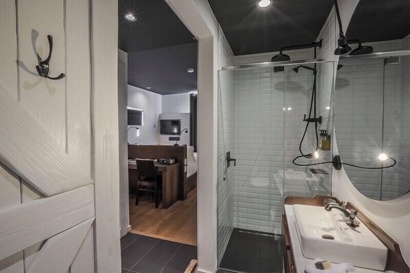 Un baño moderno con cabina de ducha de vidrio, un espejo grande y un lavabo.