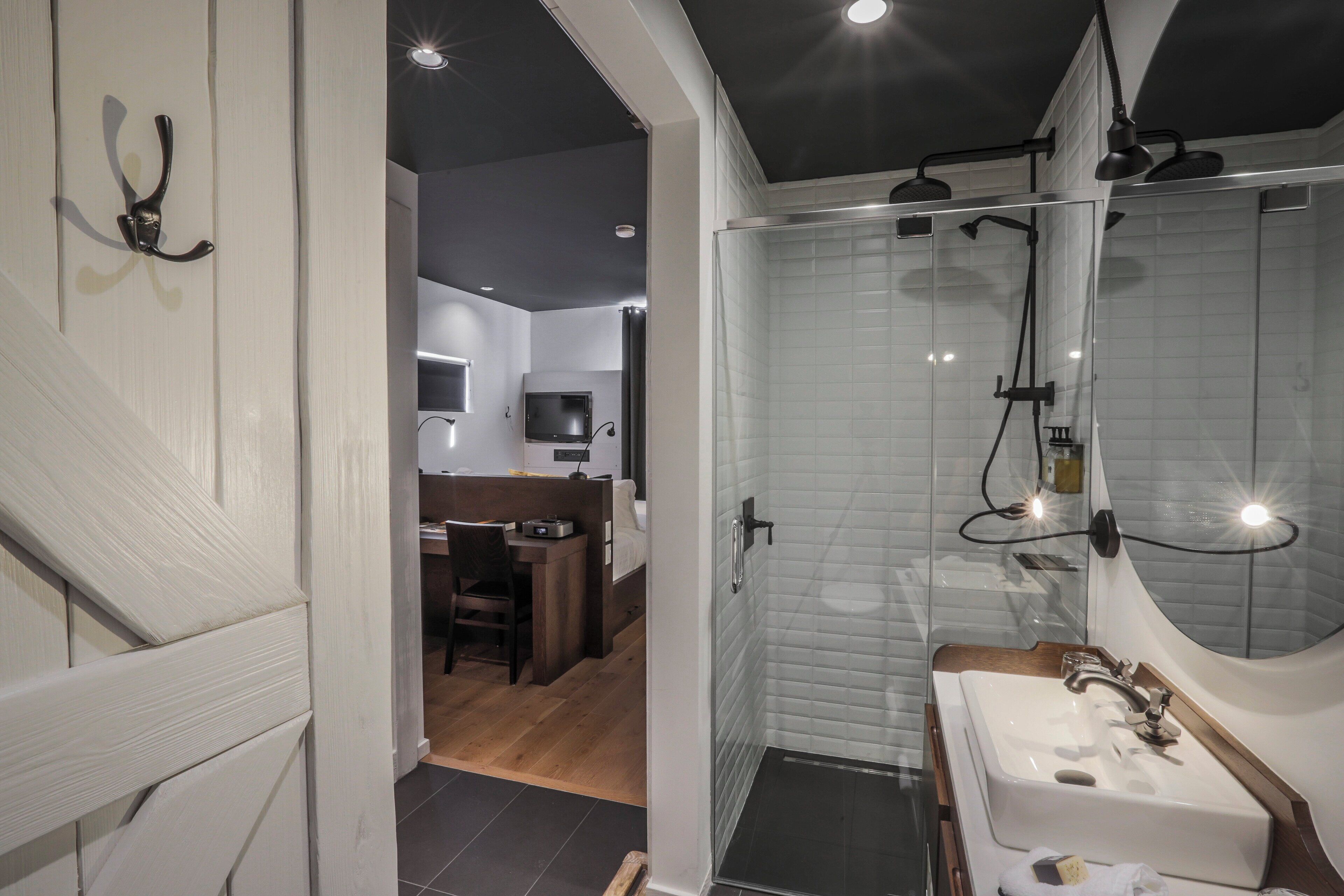 Un bagno moderno con cabina doccia in vetro, uno specchio grande e un lavandino.