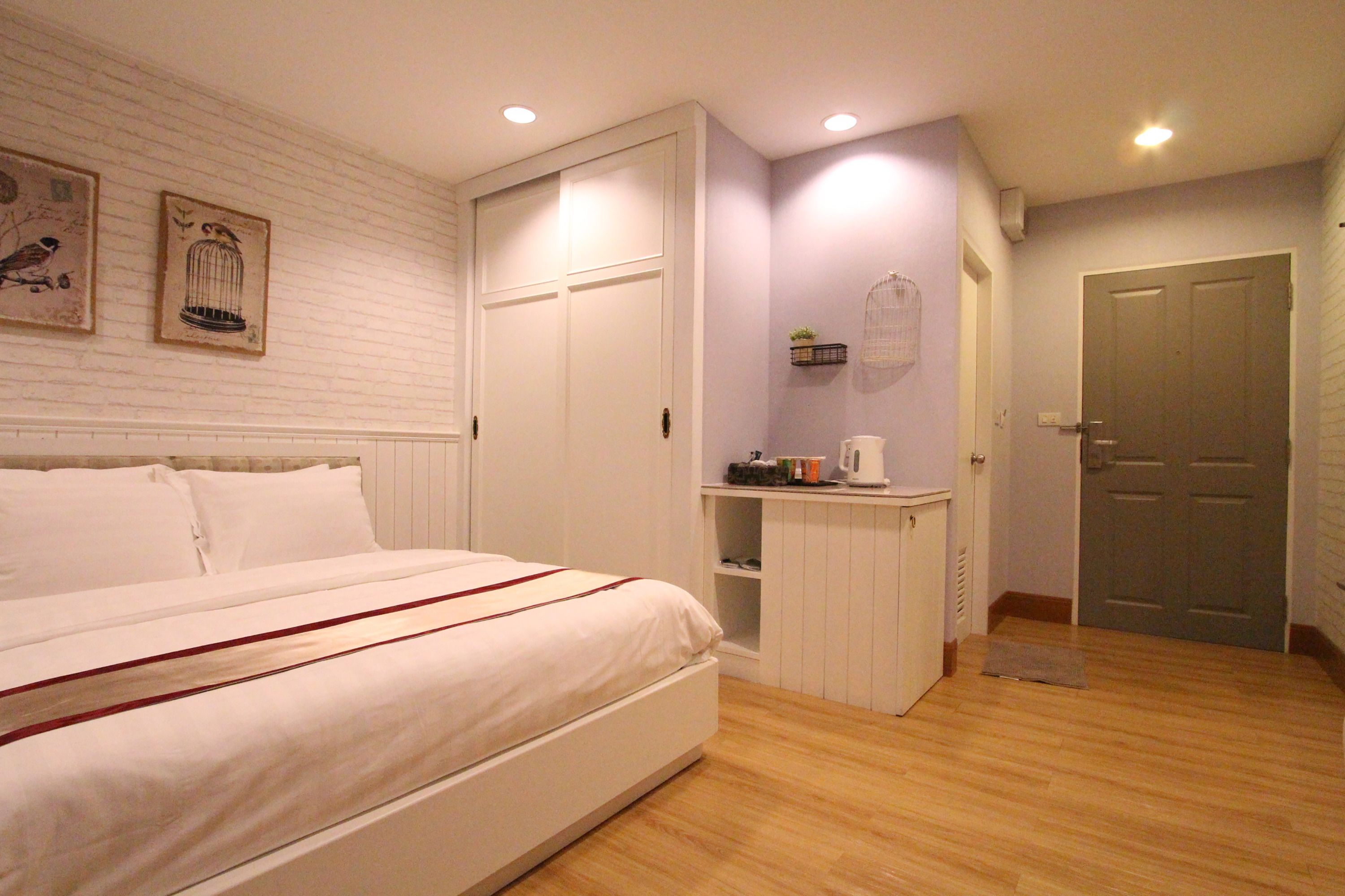 A bedroom with a bed, a wardrobe, a small kitchenette, and a door.
