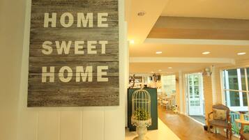 Un letrero de madera con la inscripción 'HOME SWEET HOME' y una jaula de pájaros con una planta.