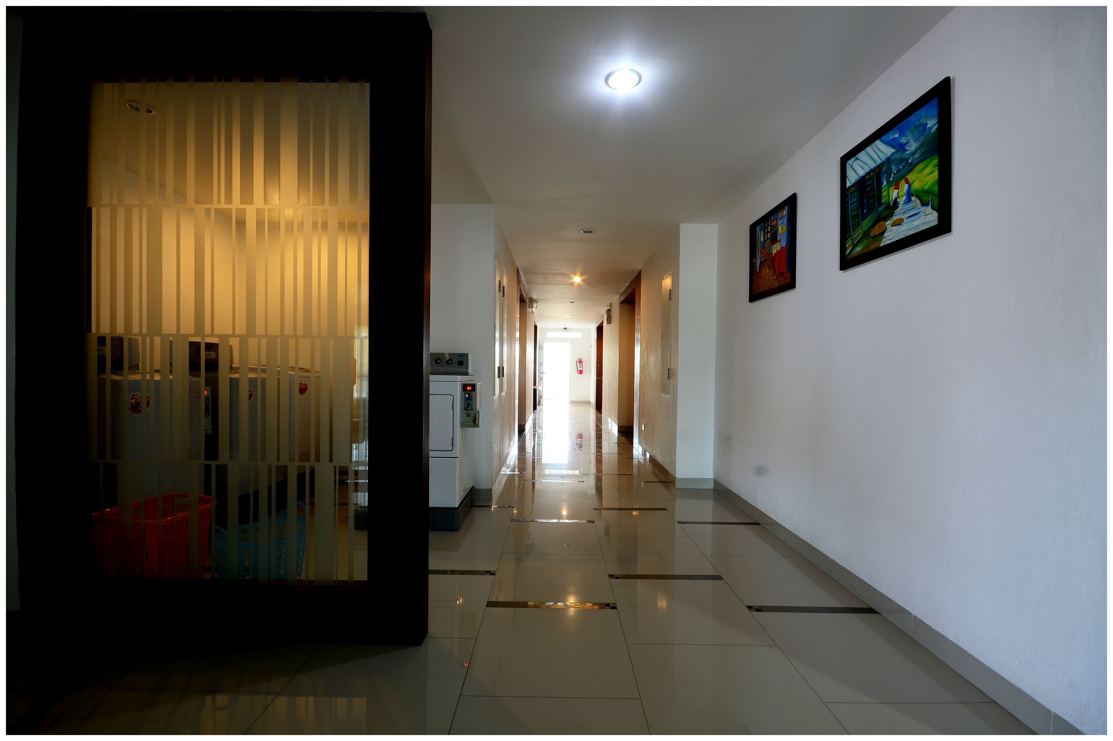 A hallway with a reflective floor, a vending machine, and a fire extinguisher.