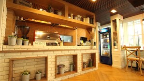 A kitchen area with a brick wall, wooden shelves, and potted plants.