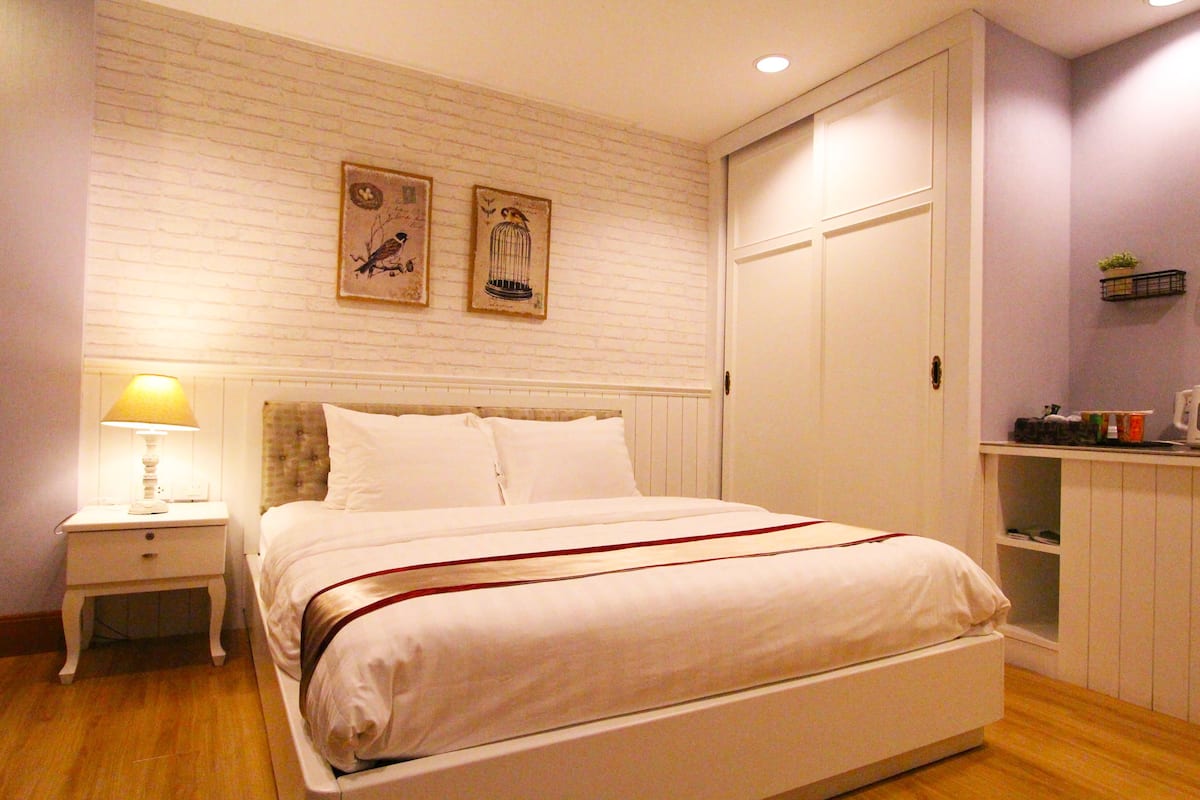 A neatly arranged bedroom with a bed, bedside table, and a nightstand.