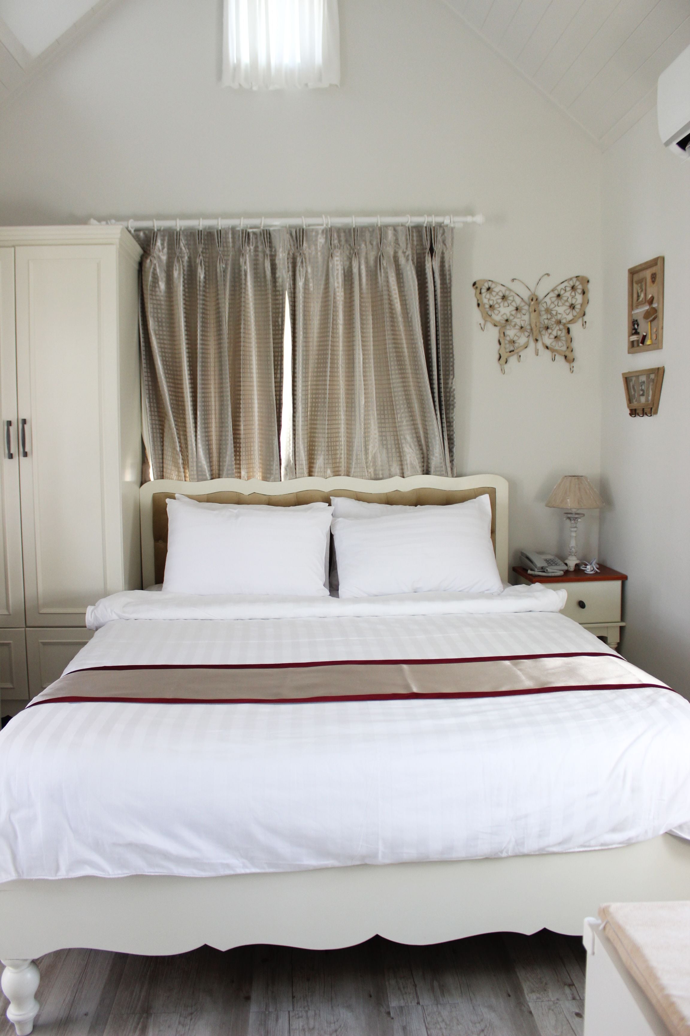 A bedroom with a bed, curtains, a nightstand, and a wall decoration.