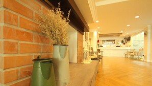 A hotel lobby with a brick wall, a reception desk, and a wooden floor.