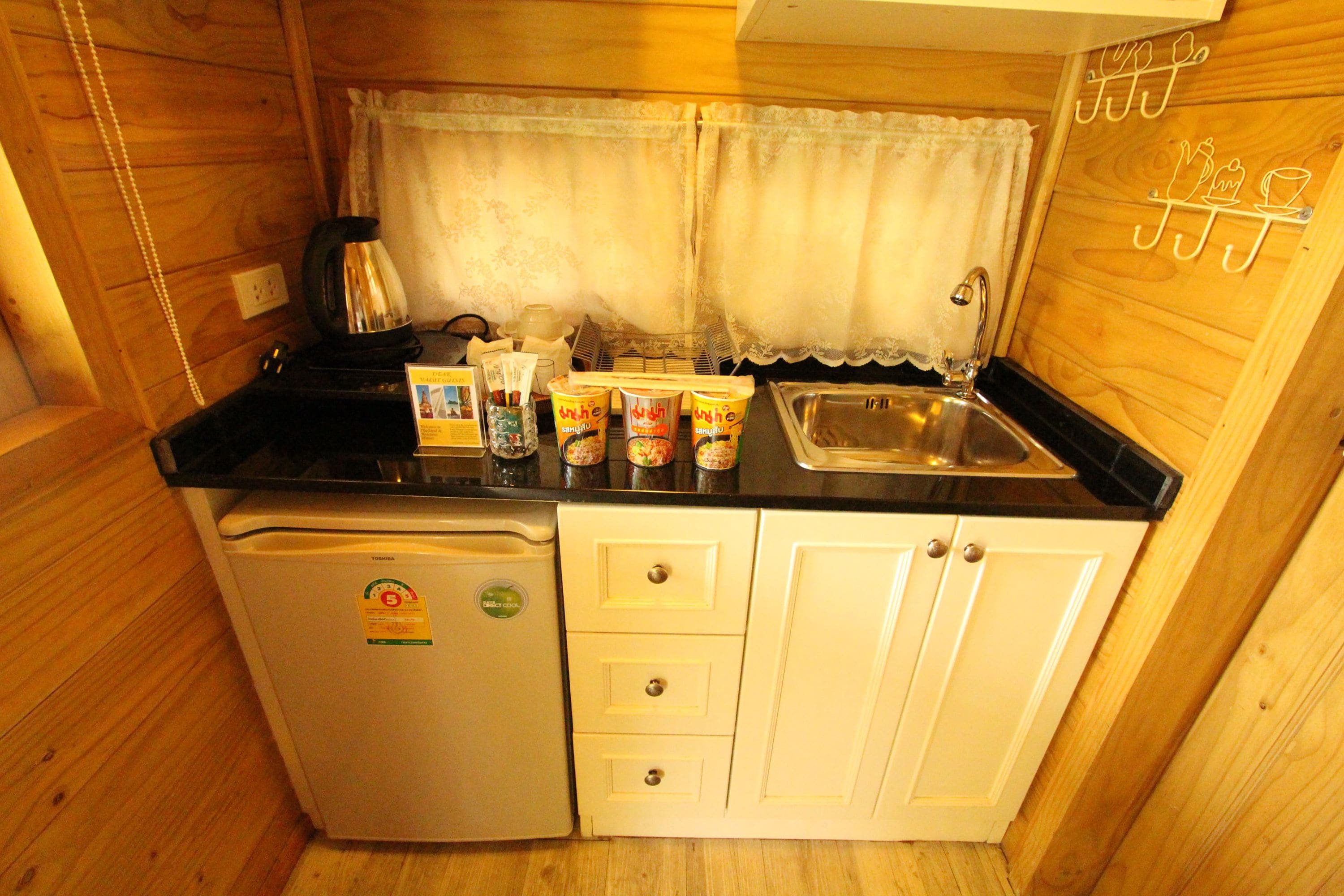A compact kitchenette with a refrigerator, a sink, and a coffee maker.