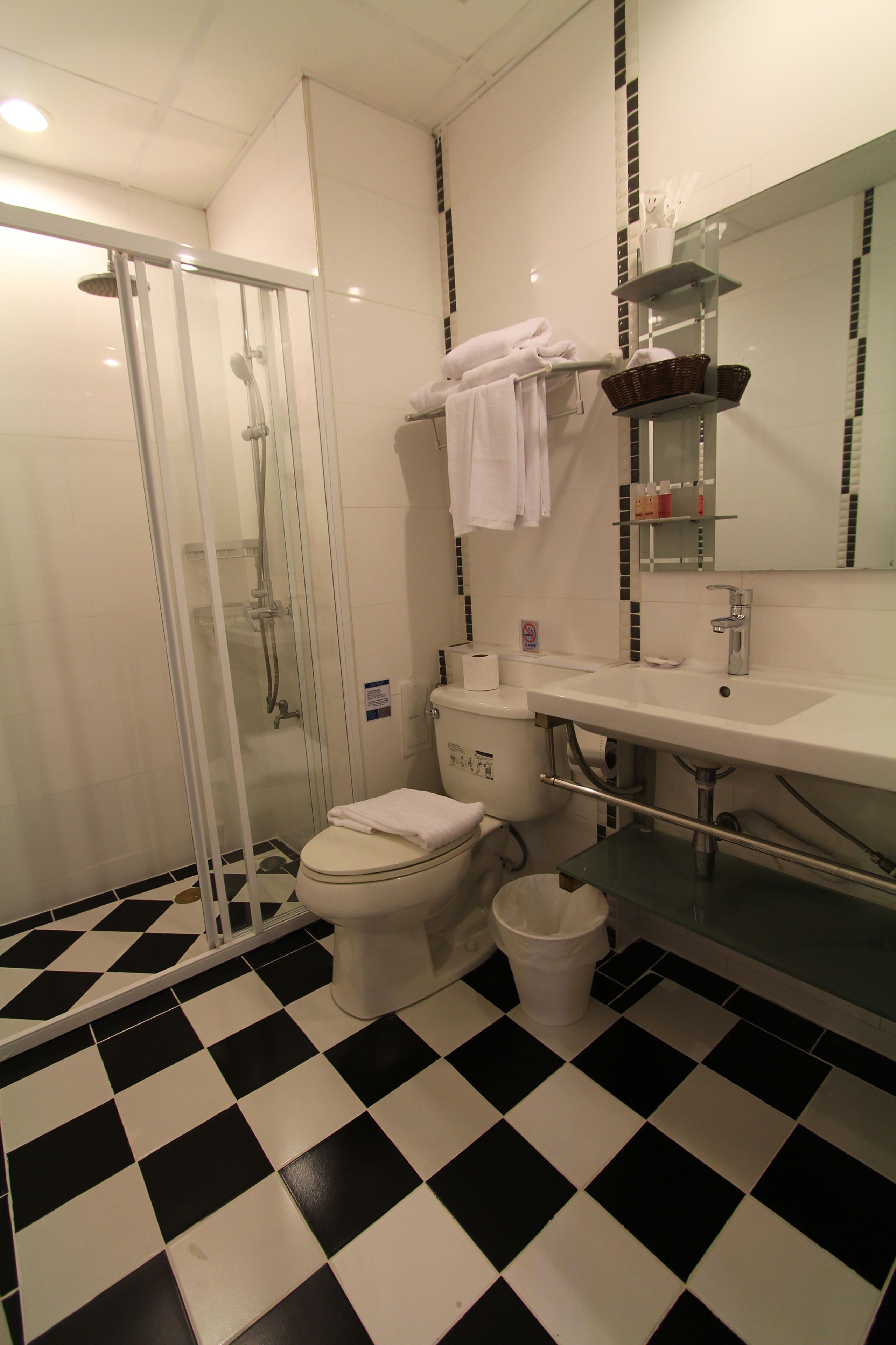Une salle de bain avec une douche à parois de verre, des toilettes et un lavabo avec un miroir au-dessus.