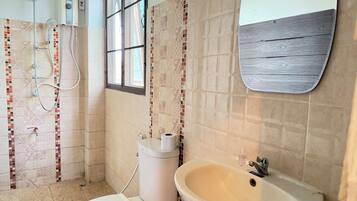 A bathroom with a shower, toilet, sink, and a window.