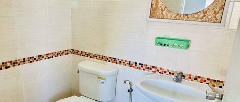 A bathroom with a toilet, sink, and mirror.