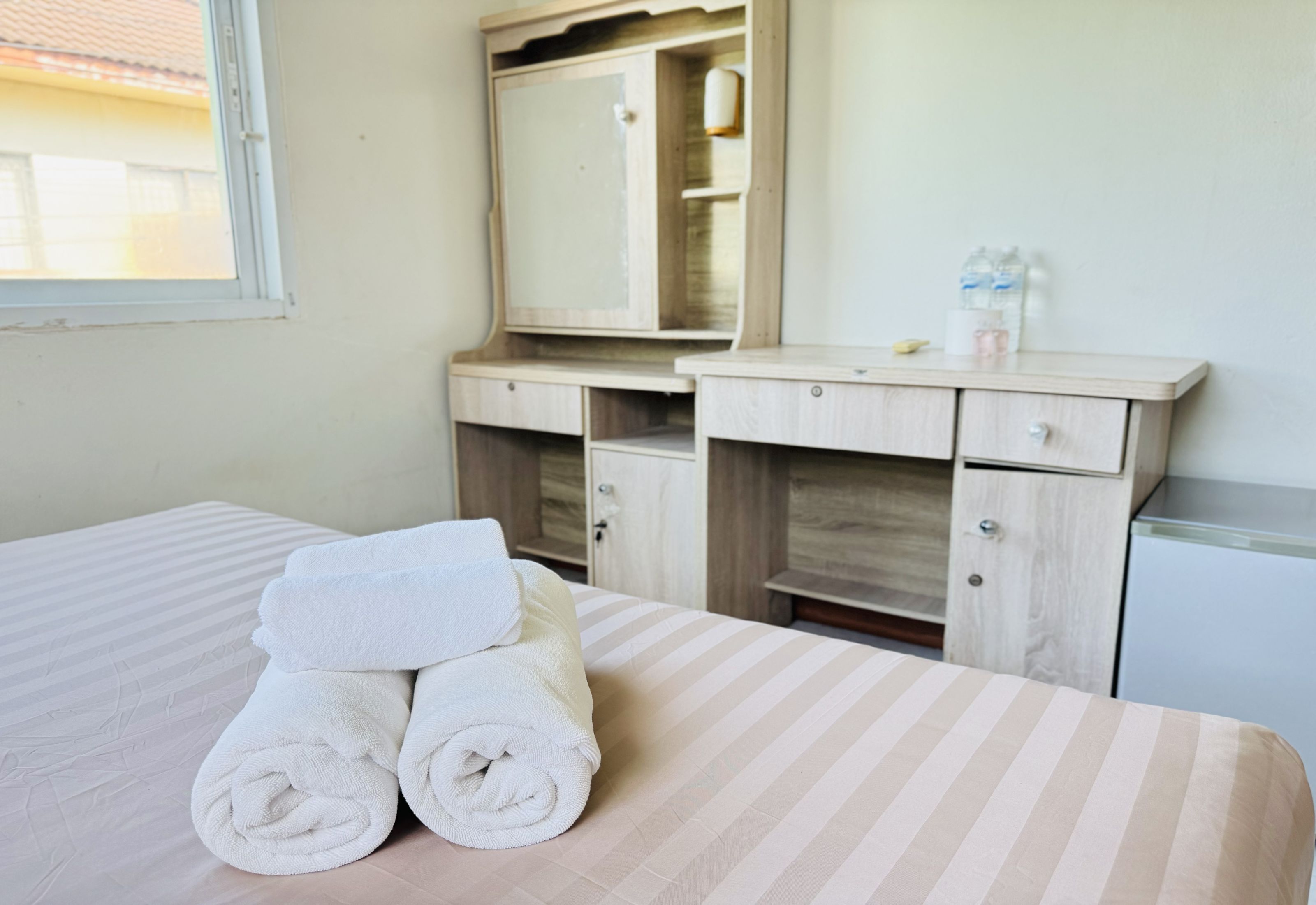 Une chambre d’hôtel avec un lit, une commode, un miroir et une fenêtre.