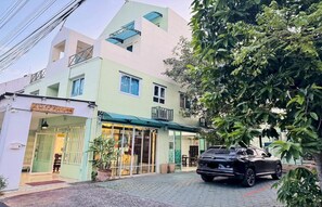 A two-story building with a green facade, a car parked in front, and a tree to the right. - Hotel O Bupatara Chiangmai (Chiang Mai)