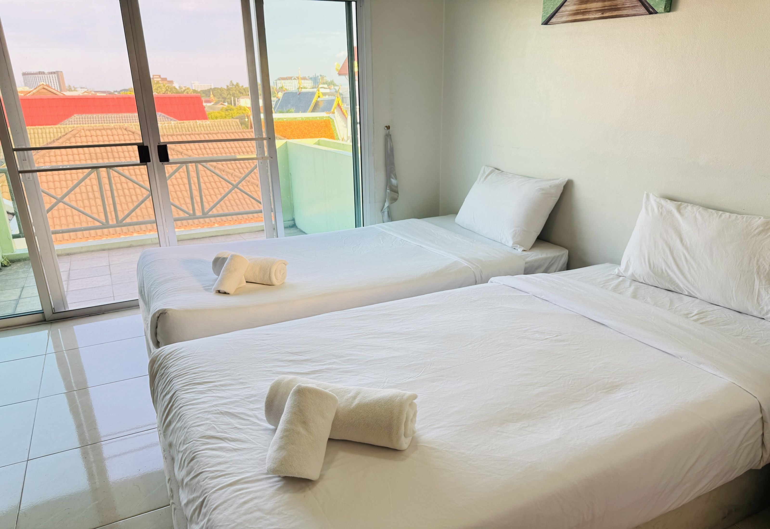 Habitación de hotel con dos camas, puerta corrediza al exterior y vistas a edificios.