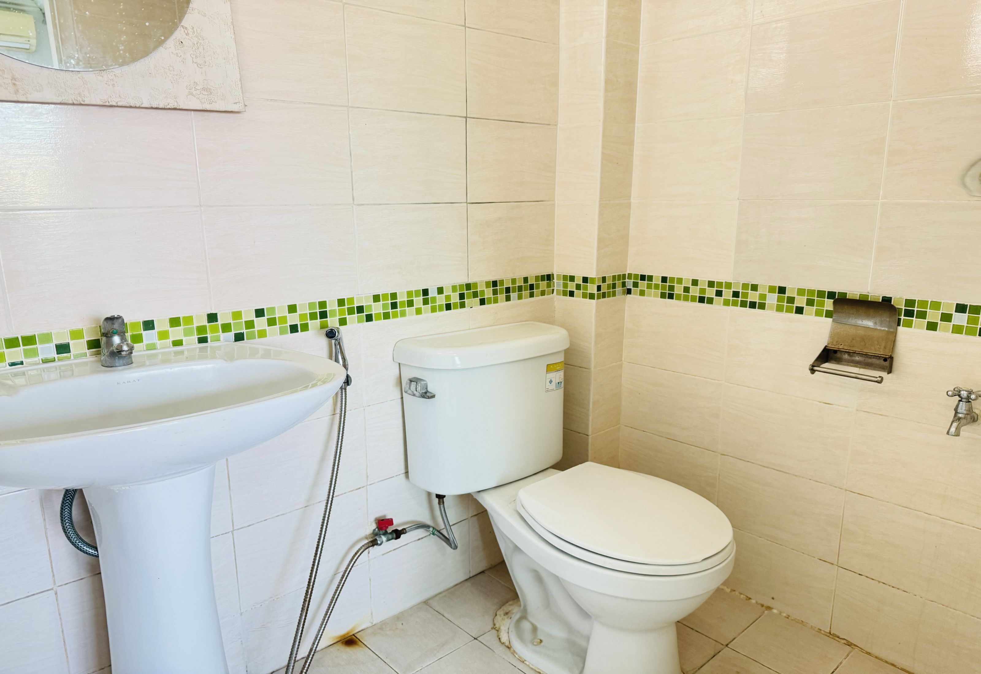 A bathroom with a sink, toilet, and a green-tiled backsplash.