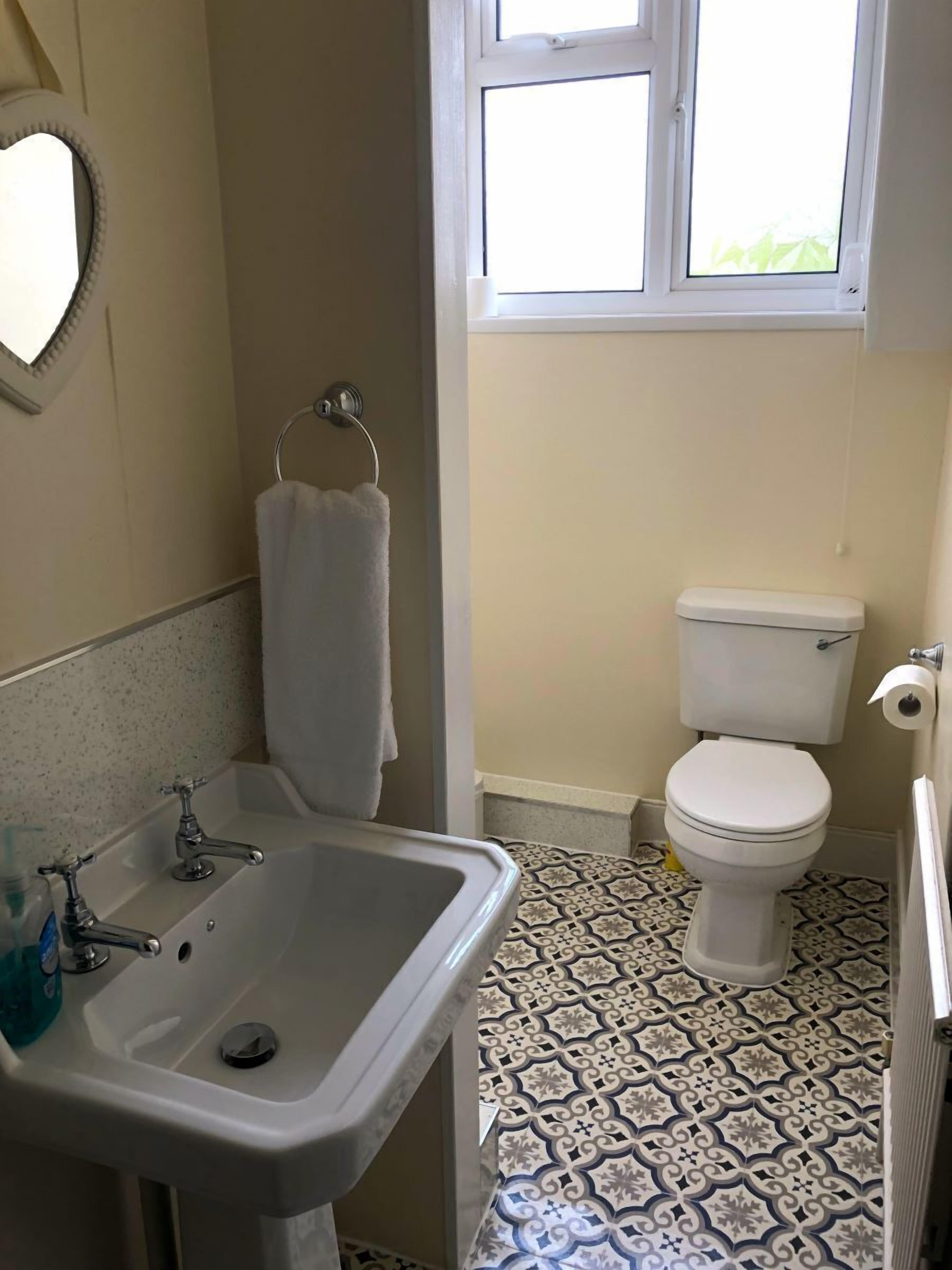 A bathroom with a sink, toilet, and patterned floor tiles.