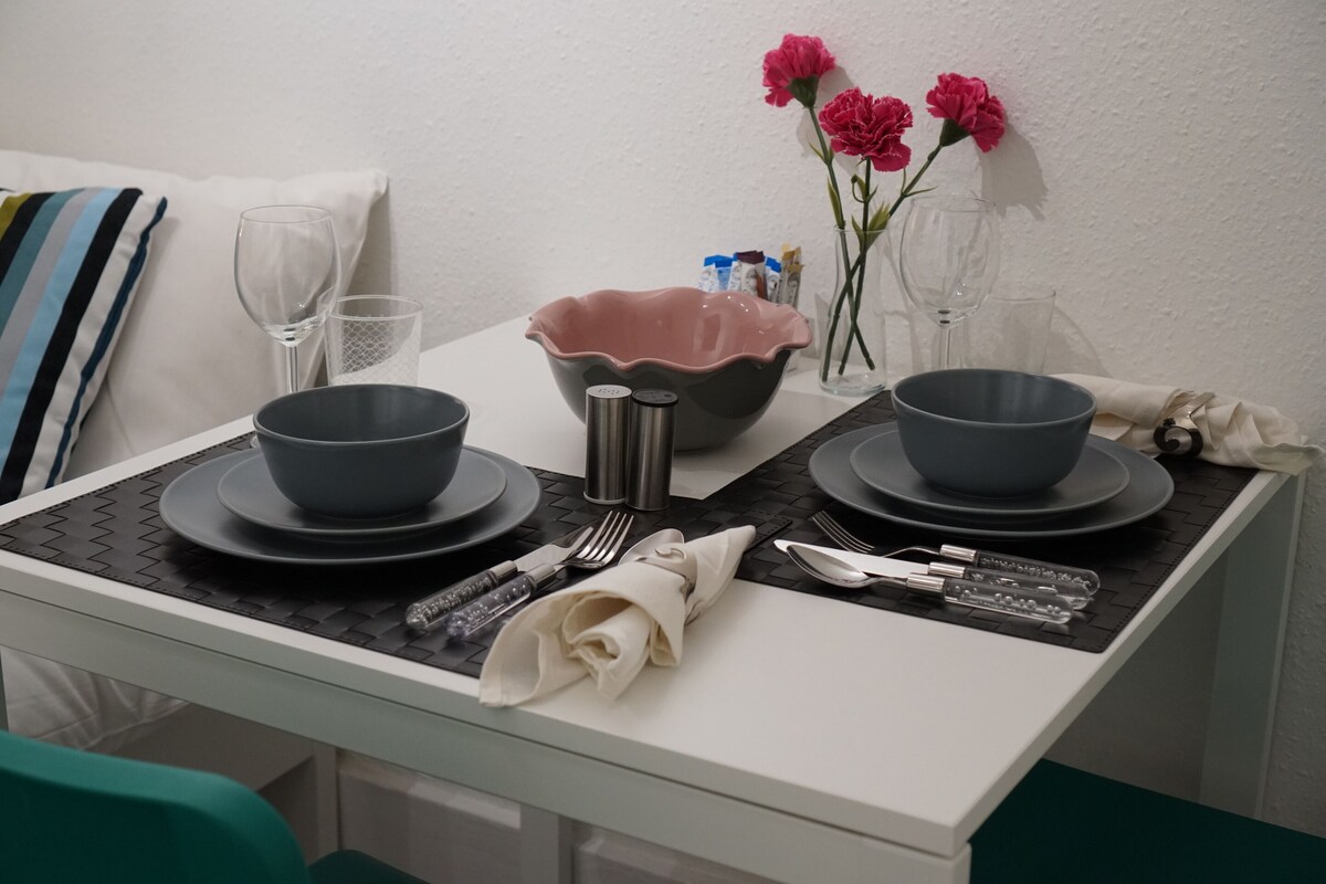 Una mesa de comedor bien puesta con dos cuencos, una jofaina y cubiertos.