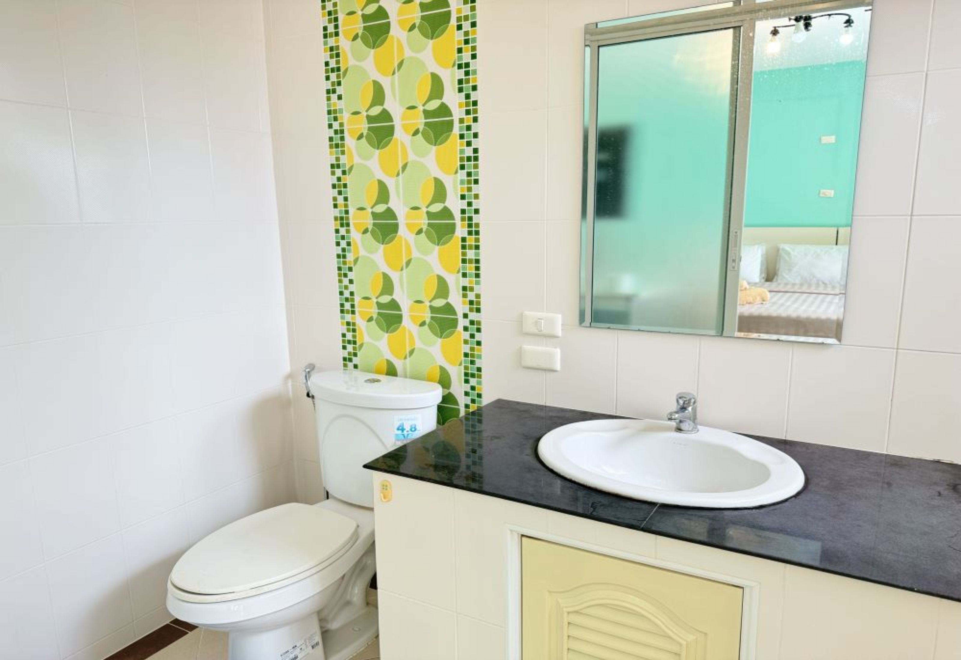 A bathroom with a toilet, a sink, and a mirror.