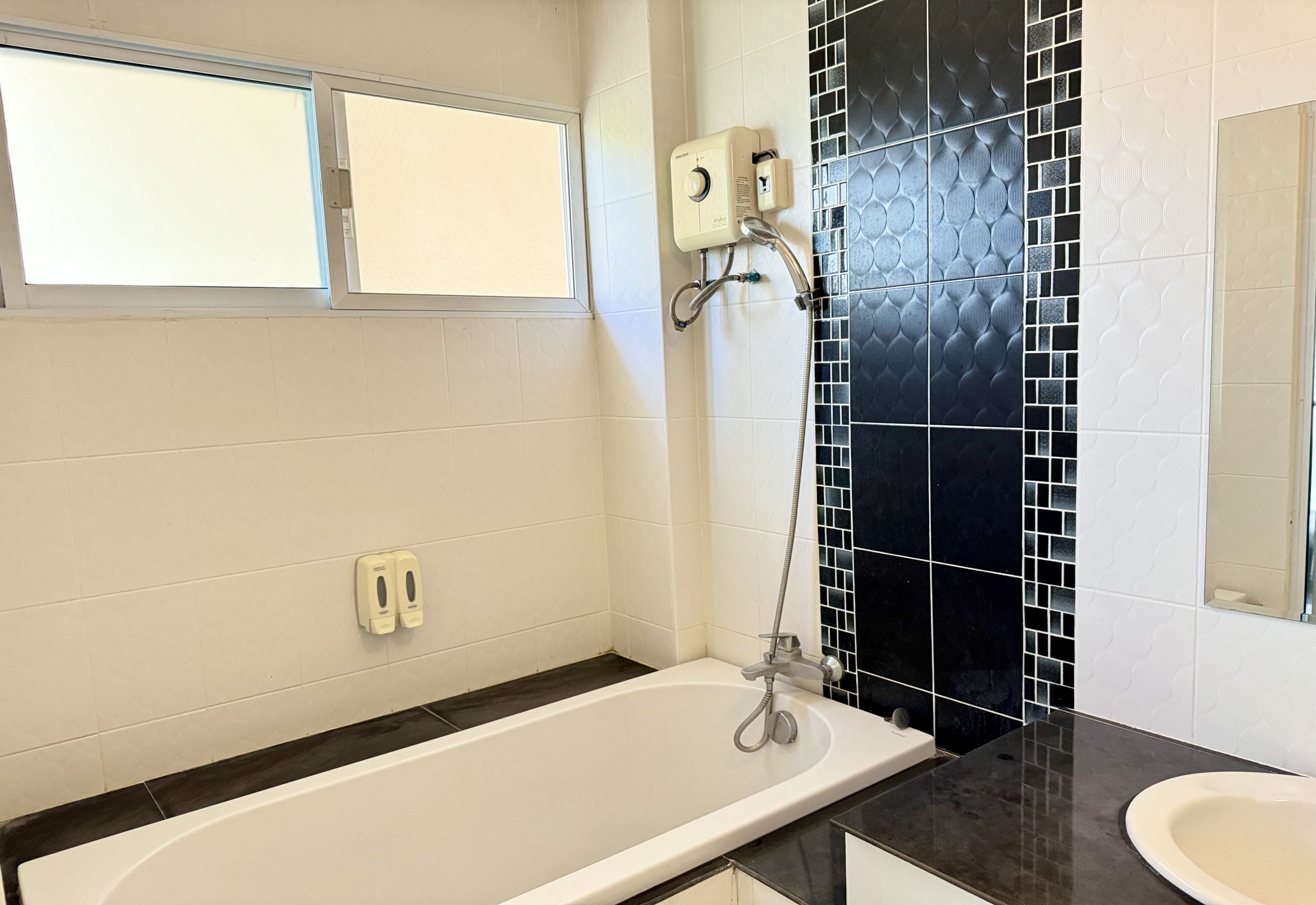 Un baño con bañera, ducha, lavamanos y espejo.