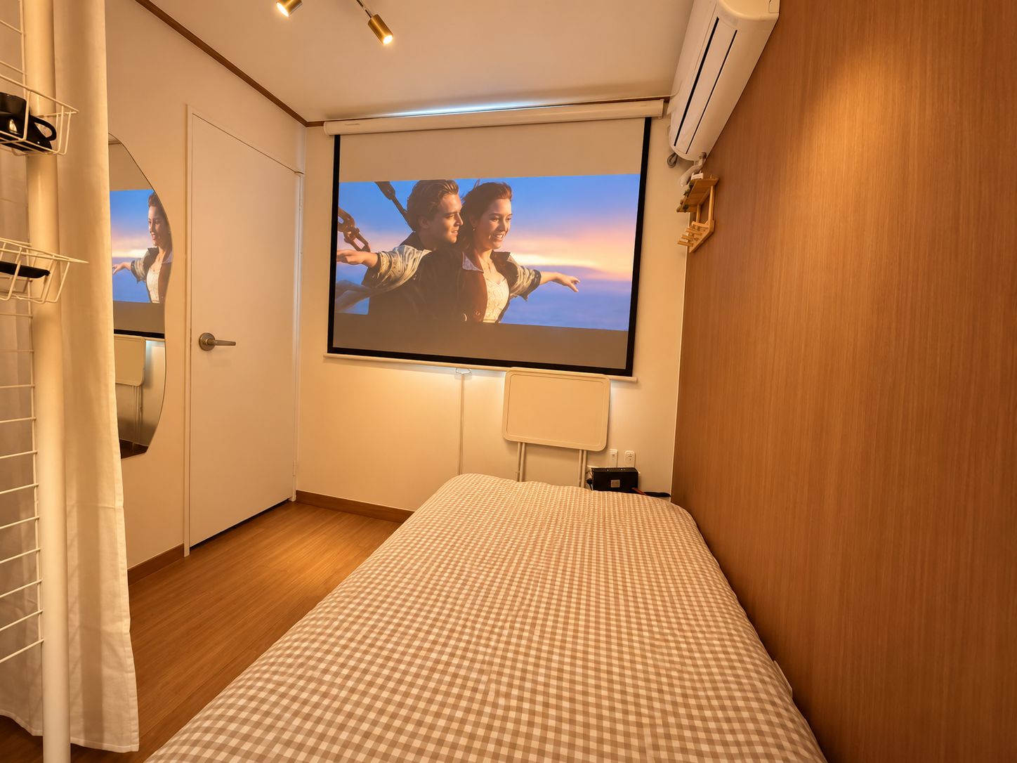 Un dormitorio con cama, televisión instalada en la pared y ventana.