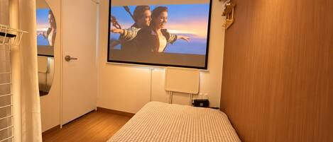 Un dormitorio con cama, televisión instalada en la pared y ventana.