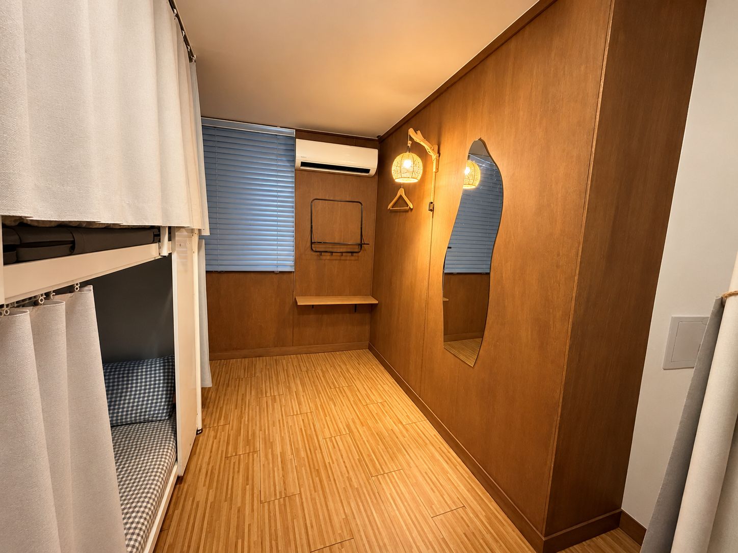 A narrow hallway with wooden walls, a bunk bed, a towel rack, and a mirror.