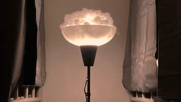 A floor lamp with a cloud-shaped shade in a room with white curtains and a bunk bed.