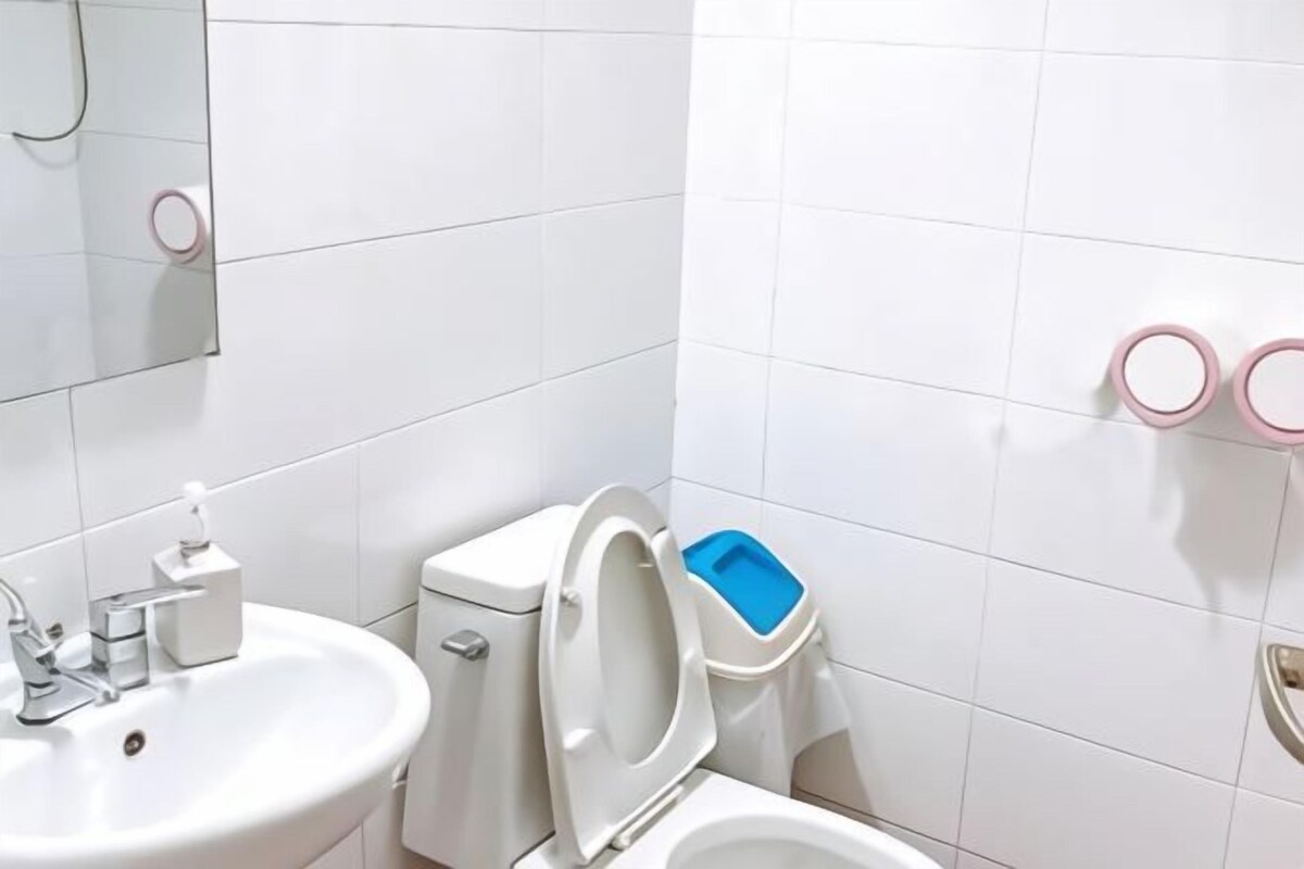 A bathroom with white tiles, a sink, a toilet, and a mirror.