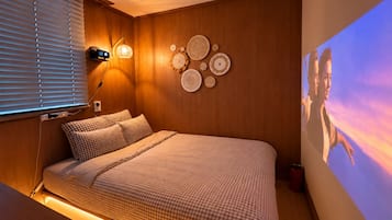 A bedroom with a bed, wall-mounted lamps, and a wall with decorative plates.