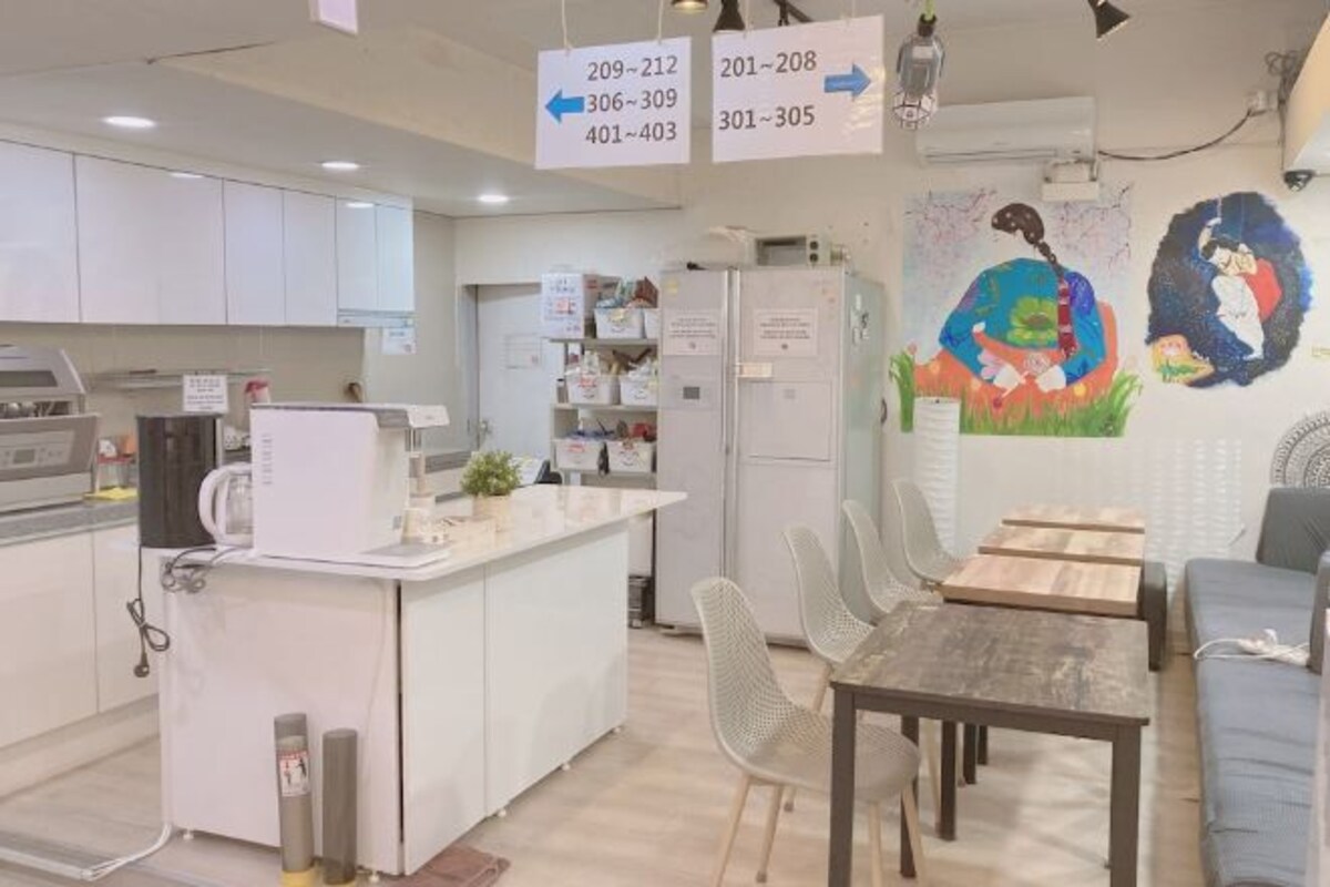 A modern kitchen with white cabinets, a central island, and a dining area with a table and chairs.
