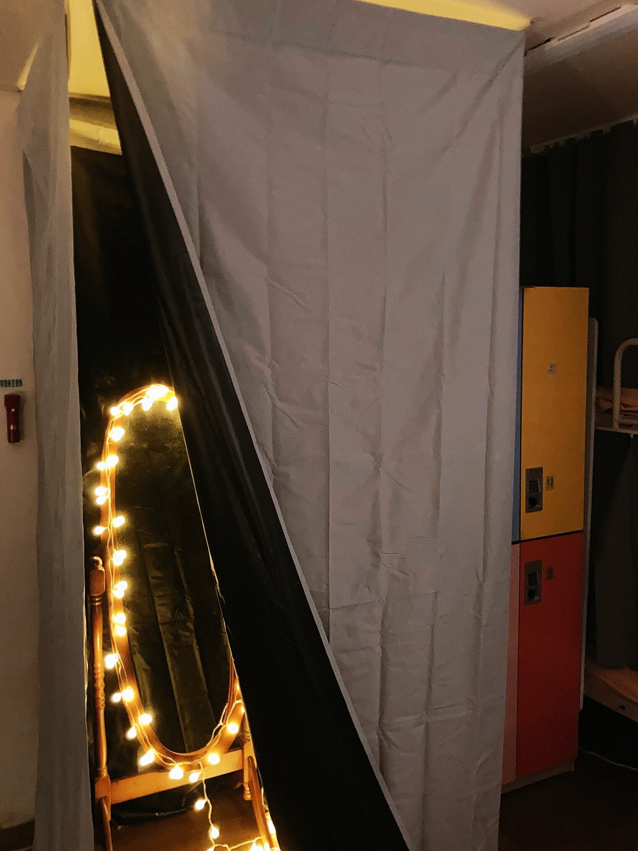 A room with a vanity mirror, a curtain, and a yellow cabinet.