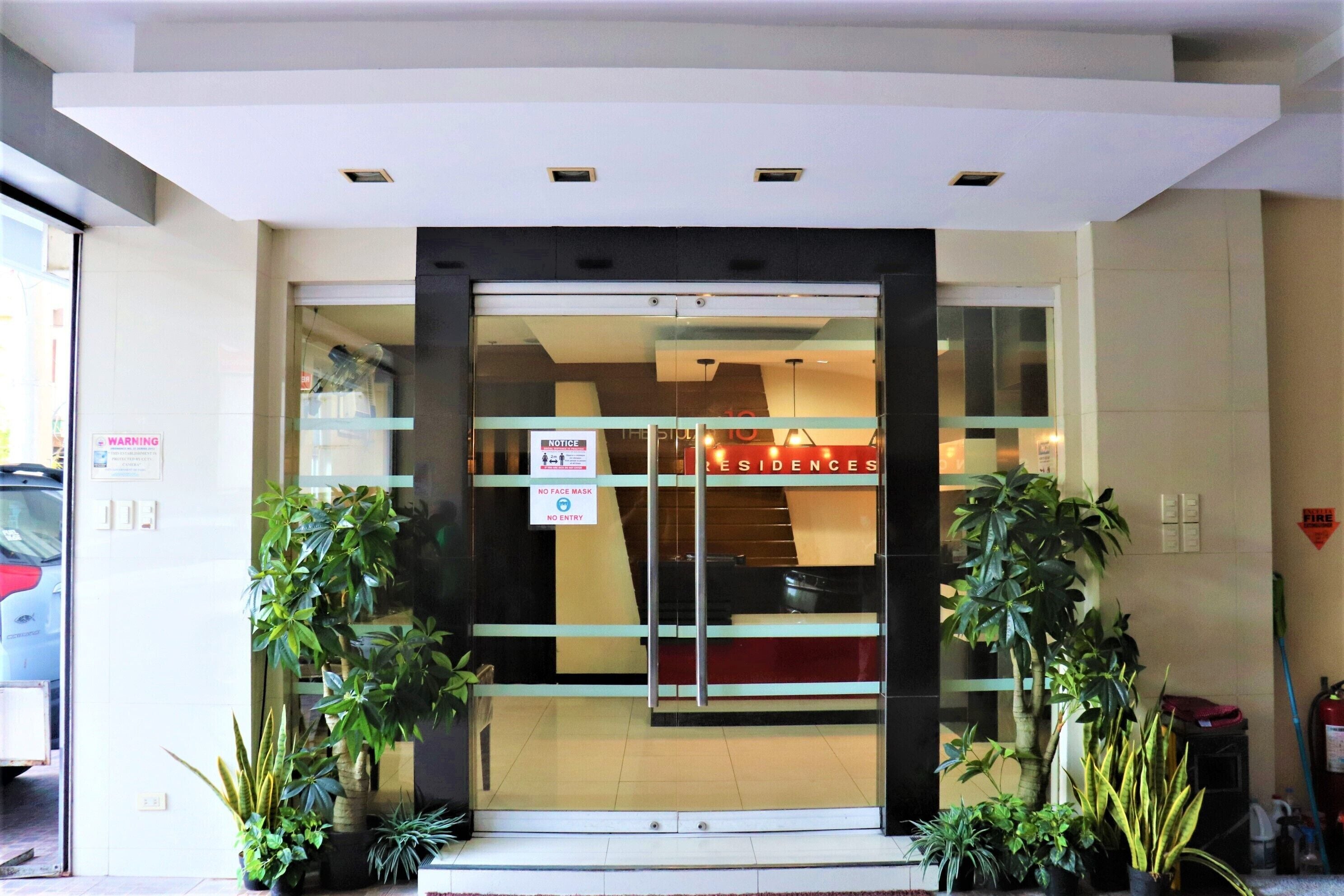 A hotel entrance with a glass door, a 'No Face Mask' sign, and 'No Entry' sign.