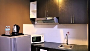 Una cocina compacta con microondas, hervidor y pileta.