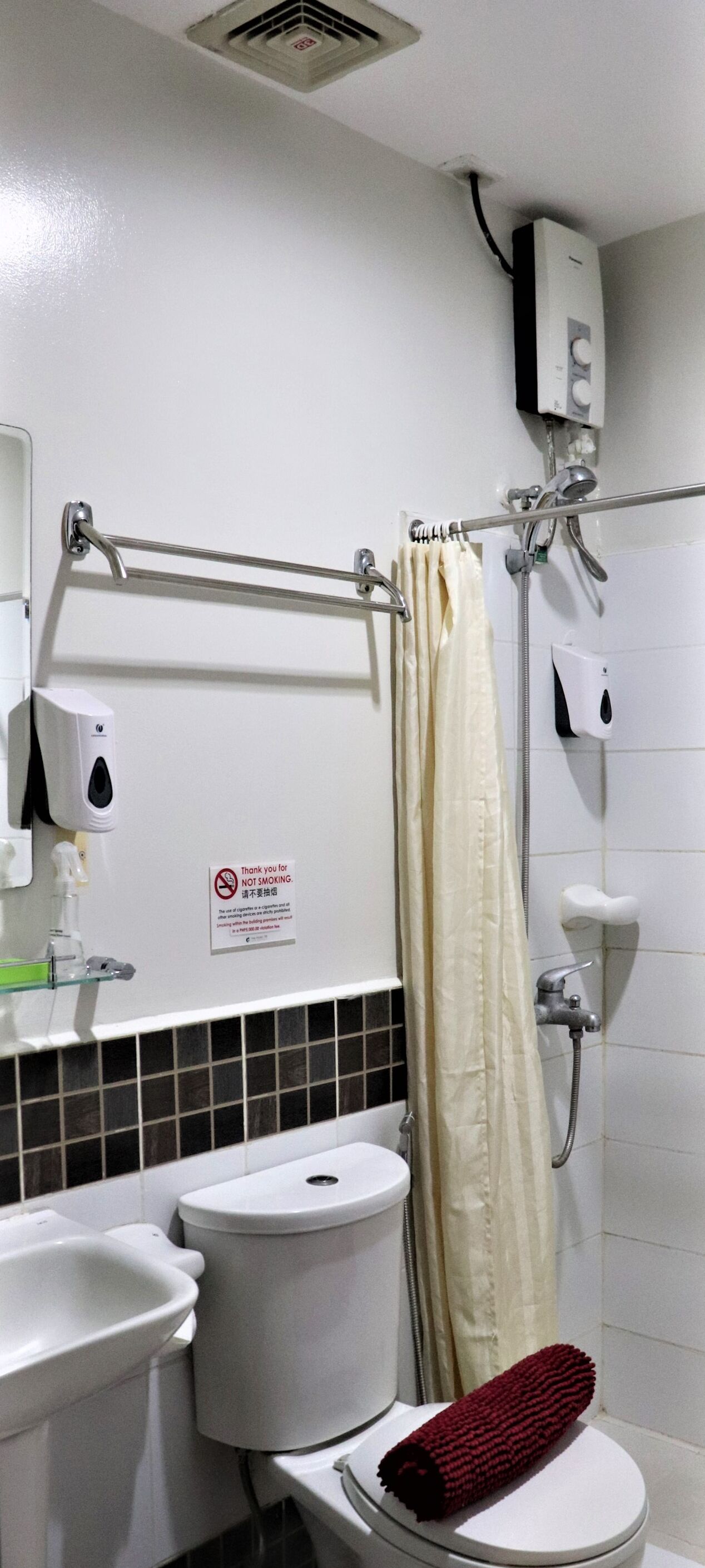 Une salle de bain équipée de toilettes, d’un bidet et d’une douche. On y trouve un panneau « Il est interdit de fumer » et un distributeur de gel hydroalcoolique.