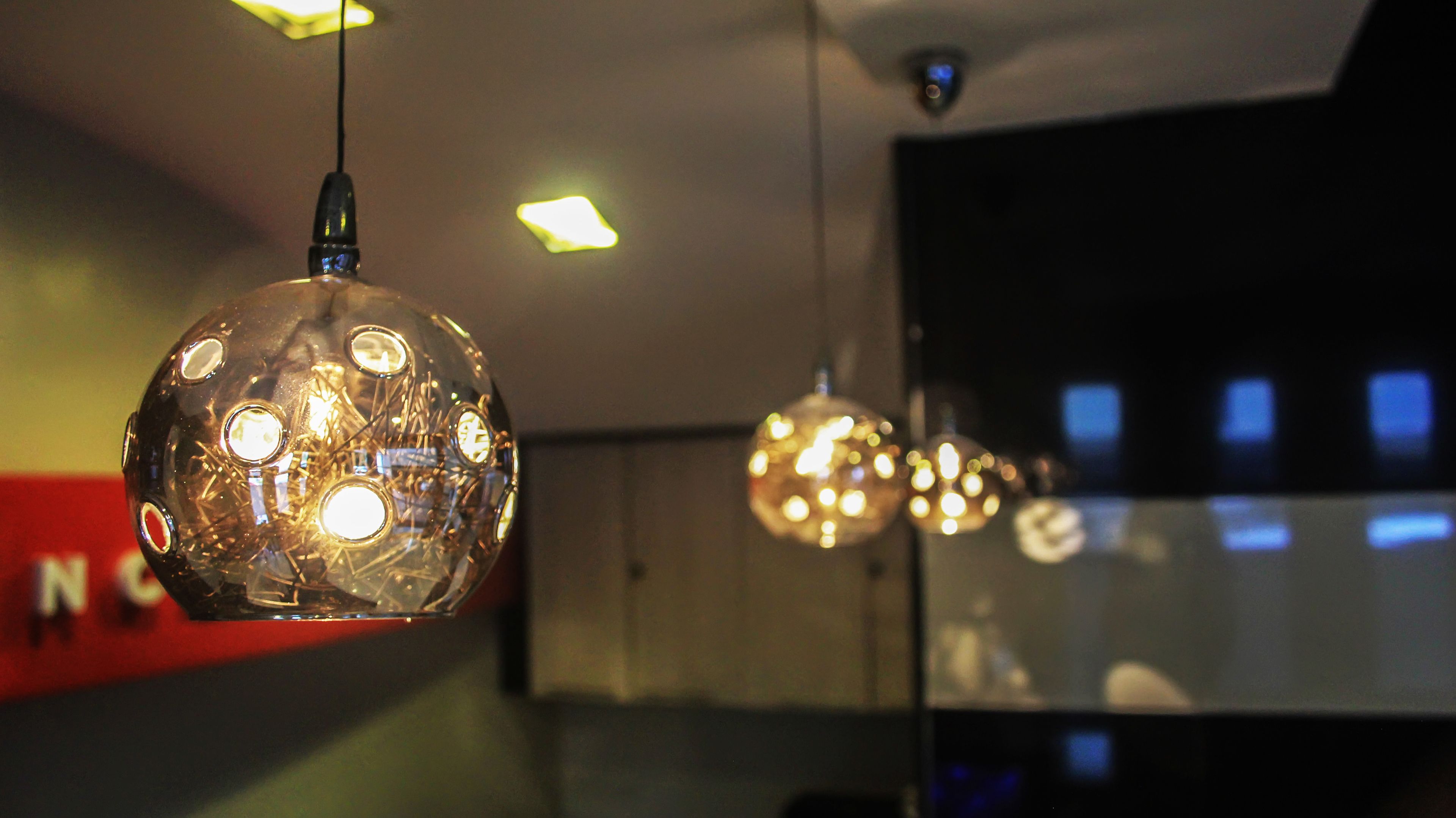 A modern interior with spherical pendant lights and a visible security camera.