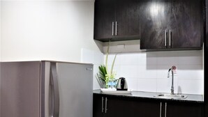 Una cocina con armarios oscuros, un refrigerador de acero inoxidable, un fregadero y una planta en maceta.