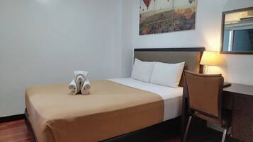 Habitación de hotel con cama, escritorio, silla y un cuadro de globos aerostáticos en la pared.