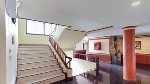 Un hall d’entrée spacieux avec un escalier, un comptoir d’accueil et une grande colonne.