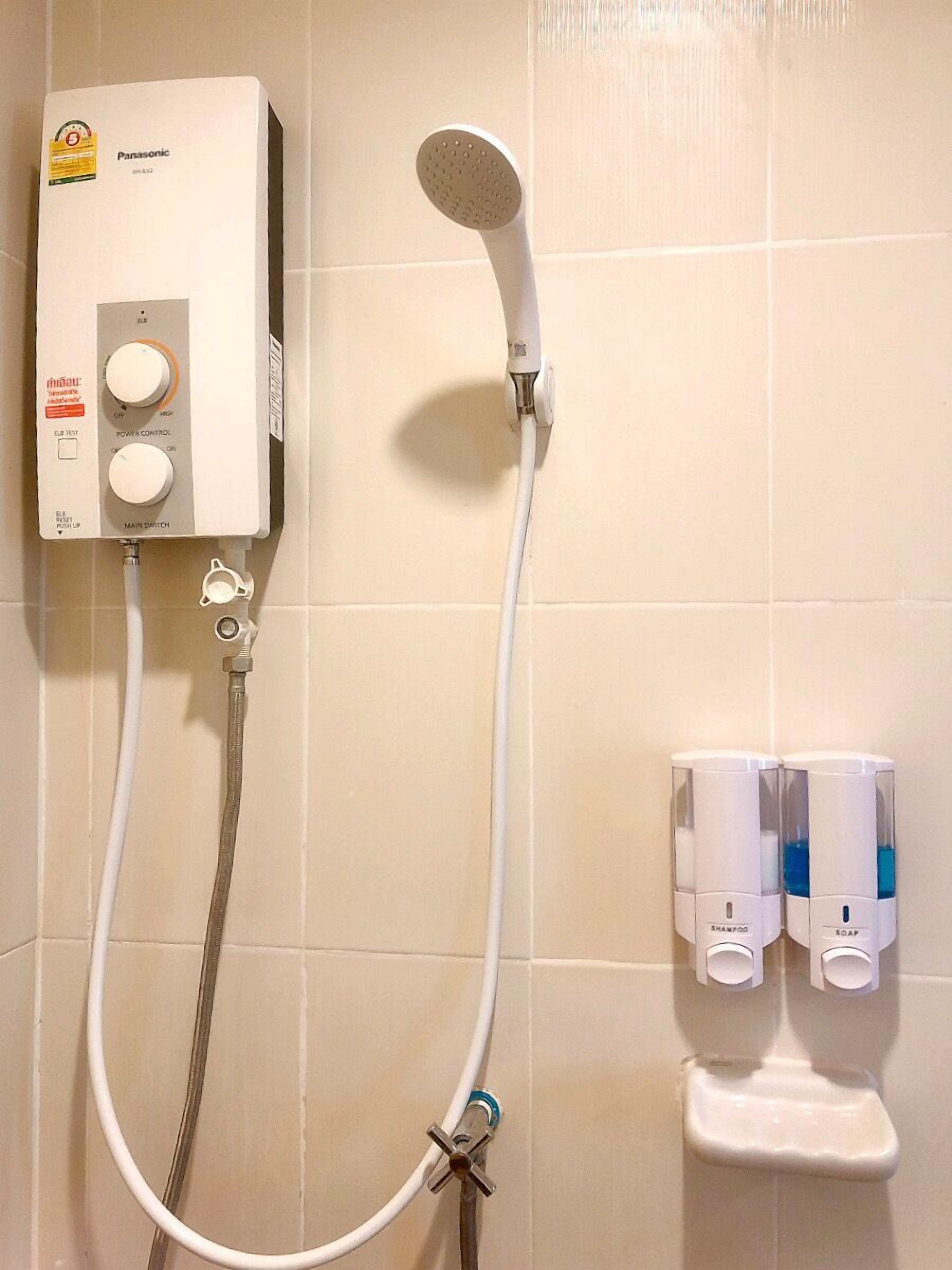 Un baño con una ducha blanca, un cabezal de ducha de mano y dos dispensadores de jabón.