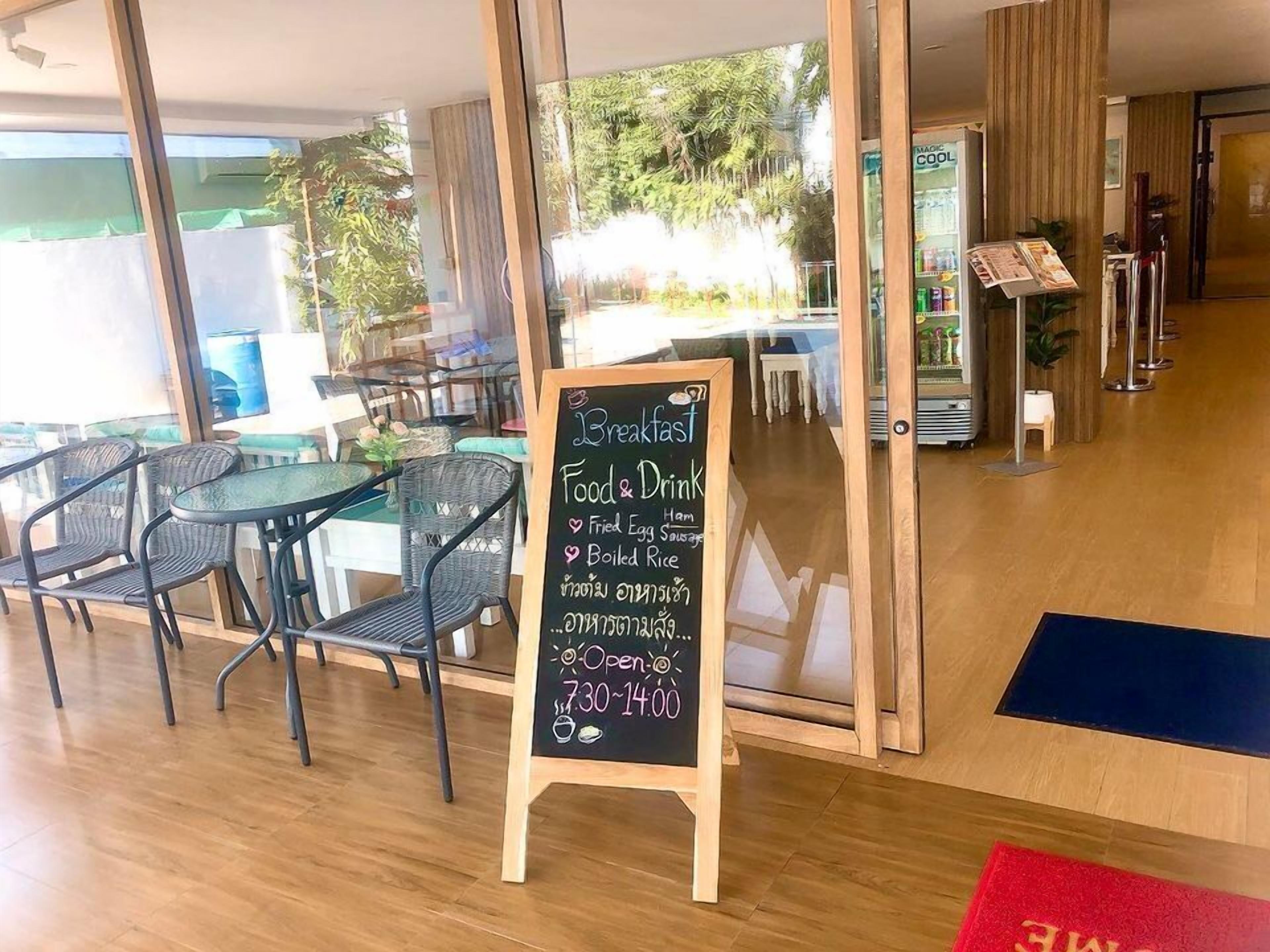 A breakfast menu board with food and drink options, a wooden floor, and a view of the outside.