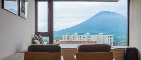 Habitación con un ventanal grande que ofrece vistas a una montaña y edificios.