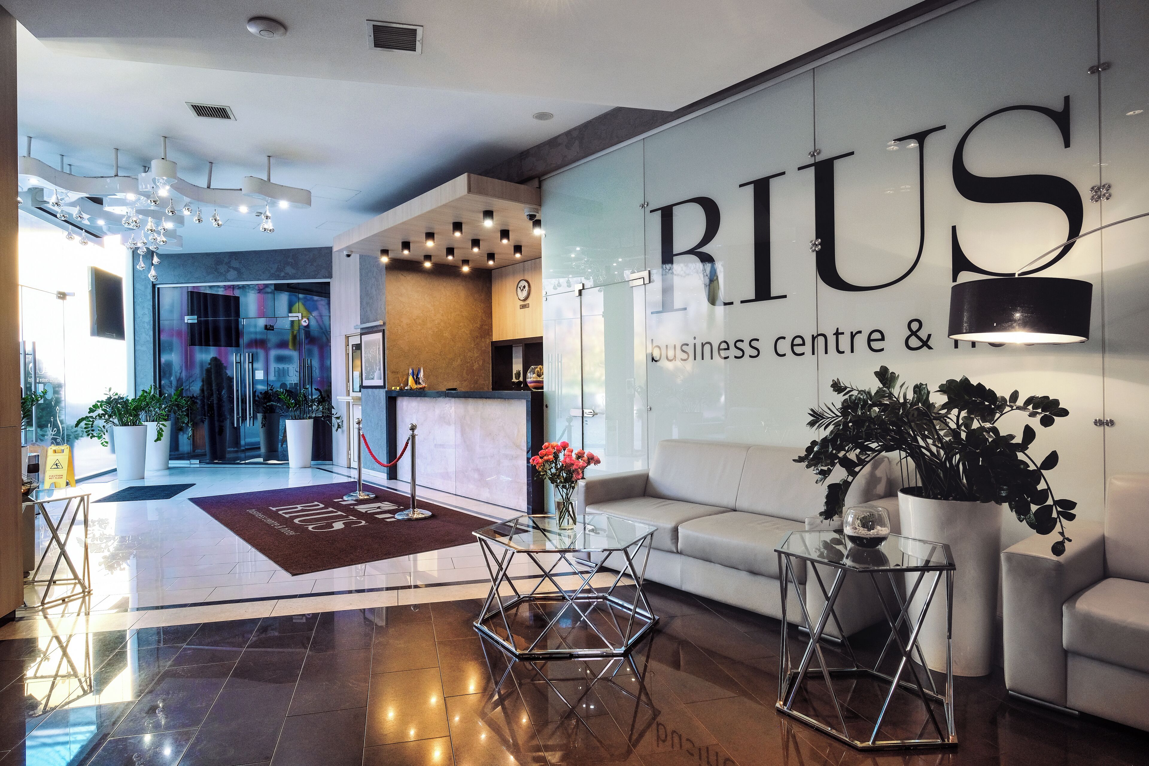 Eine moderne Lobby mit einer Glasschrankwand, die den Namen 'RIUS business centre &' zeigt.